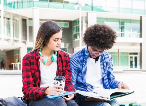 young-diverse-couple-sitting-outside-college-building_23-2148093344