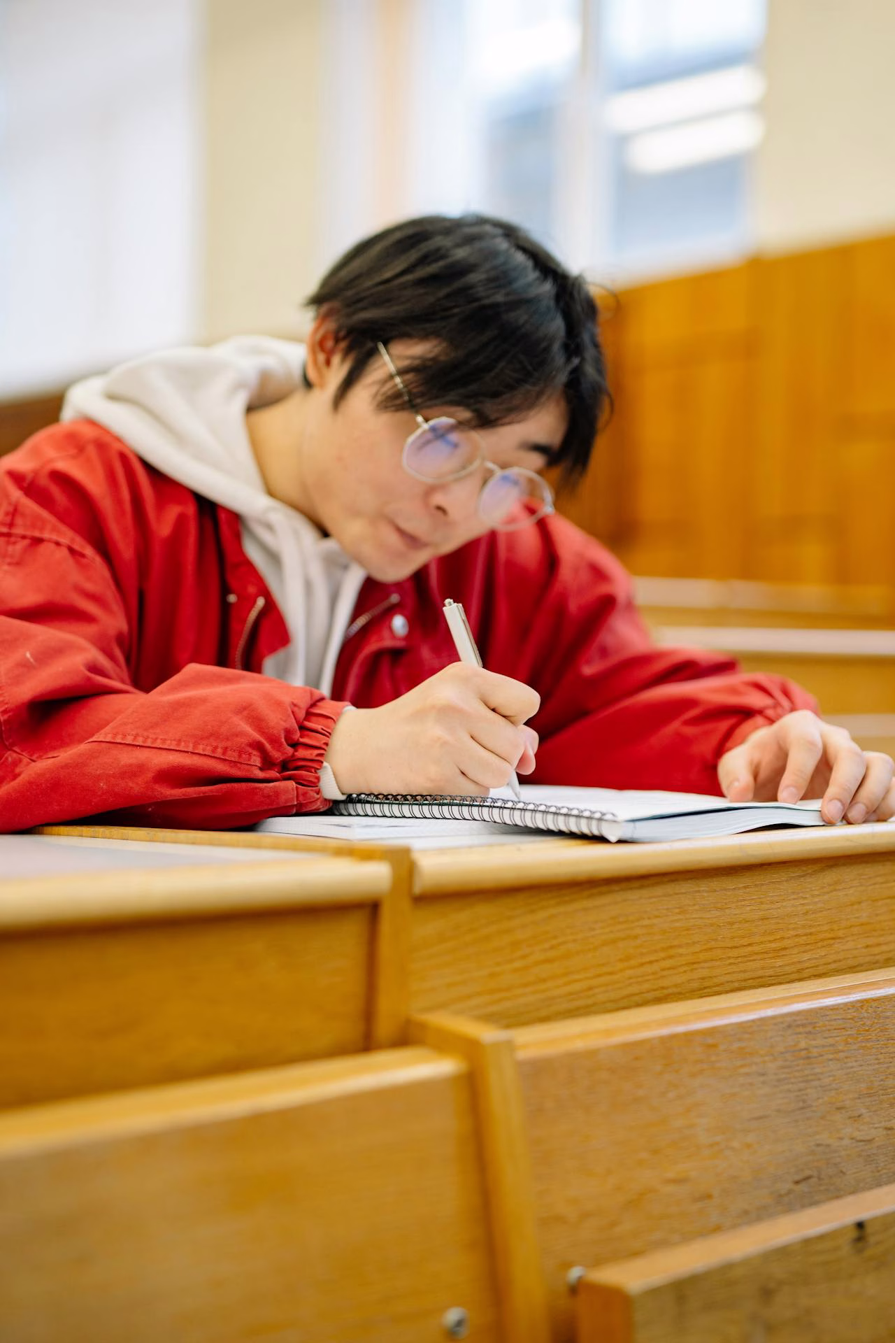 Pearson Edexcel International AS student writing notes in a lecture hall