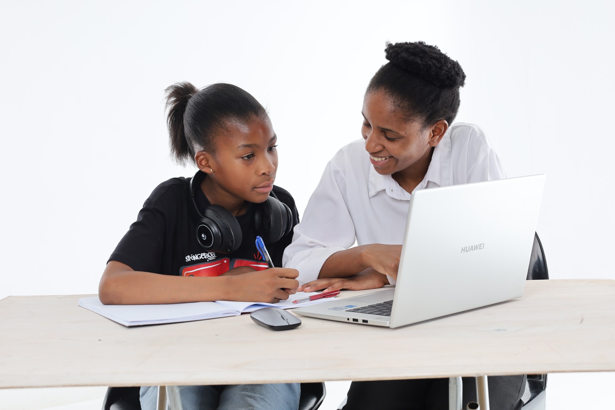An Apex Academic Centre tutor leaning in to help a young South African learner with her work