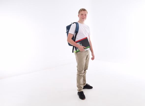 A South African high school learner standing with a backpack and carrying his books
