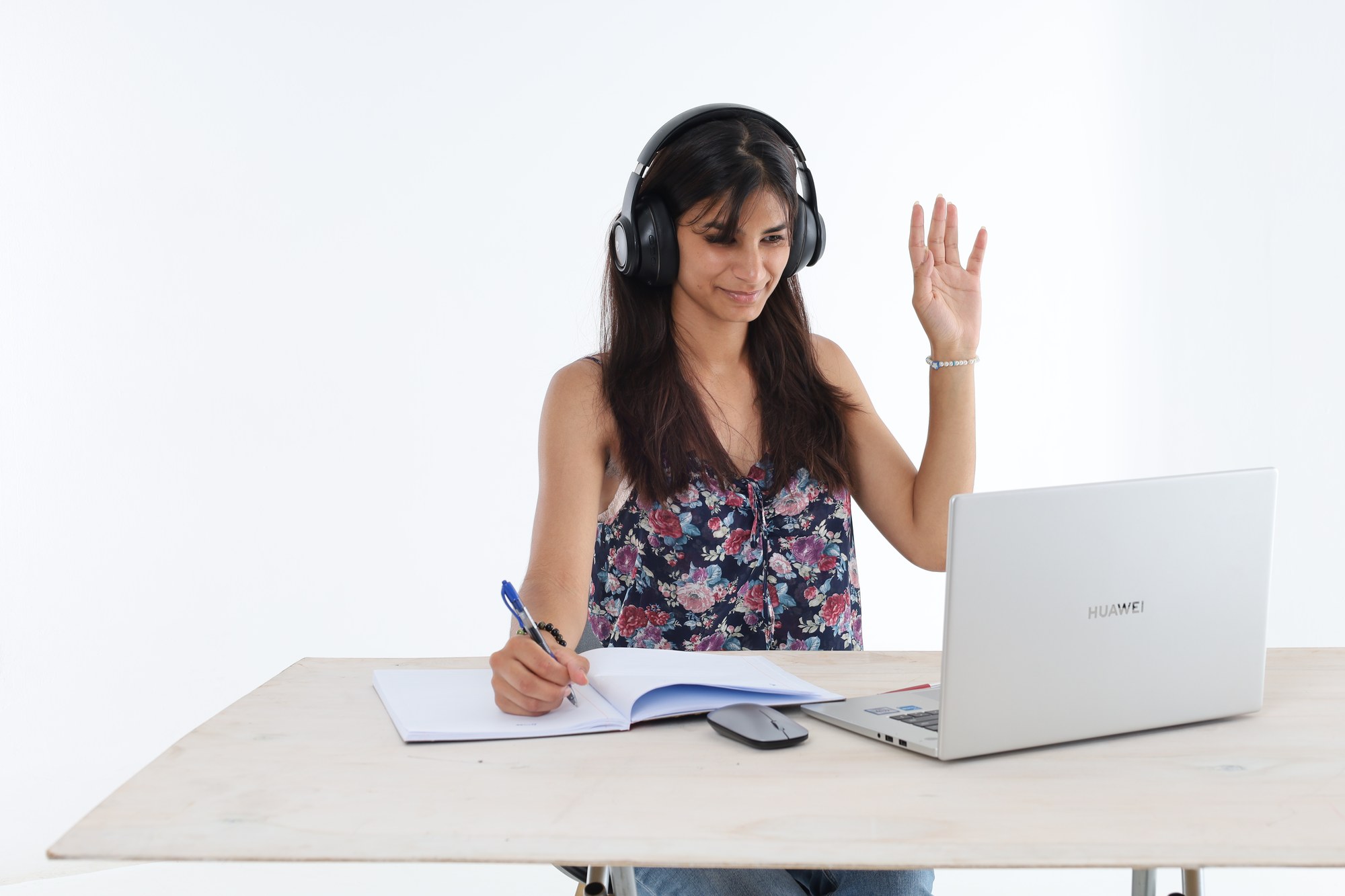 A South African student wearing headphones and raising her hand to ask a question during an online lesson