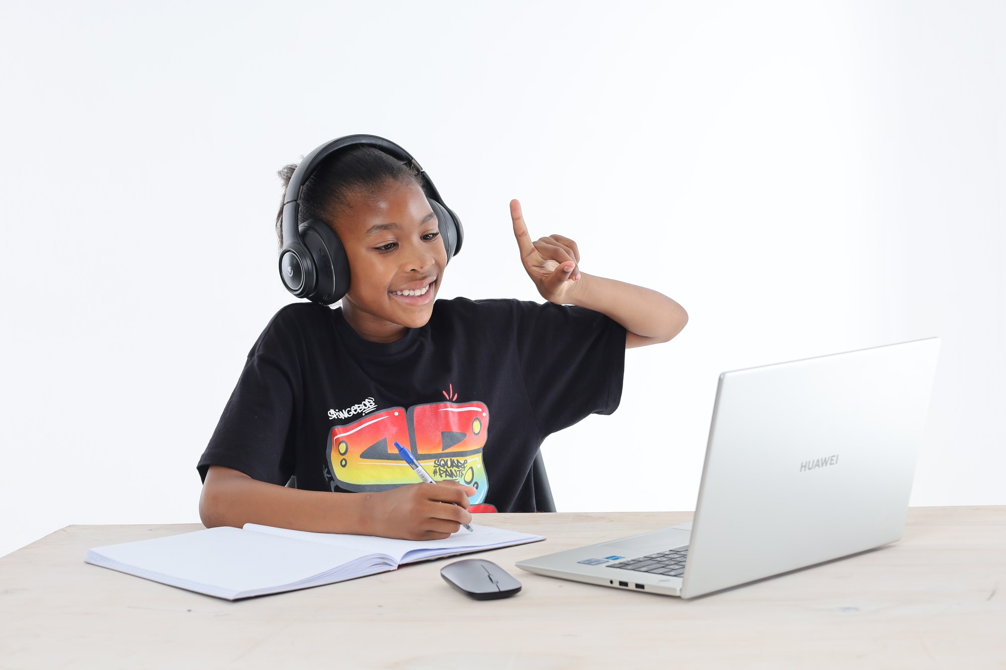 A young South African learner wearing headphones and raising her hand to answer during an online lesson