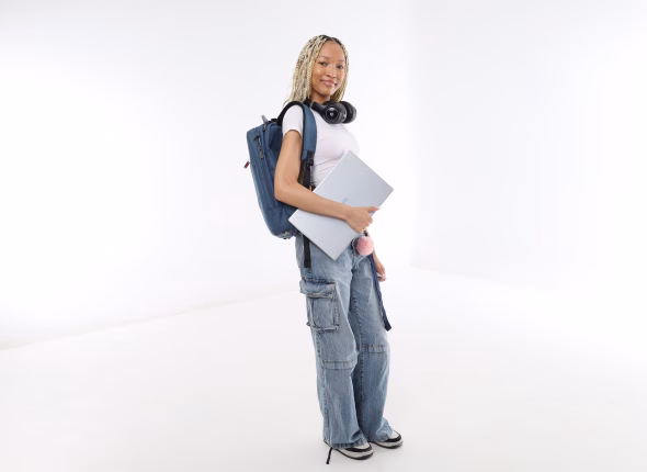 A South African student standing with a backpack, headphones and a laptop under her arm