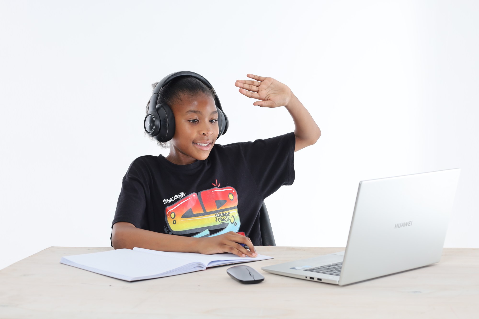 A young South African learner wearing headphones and taking part in an online tutoring lesson
